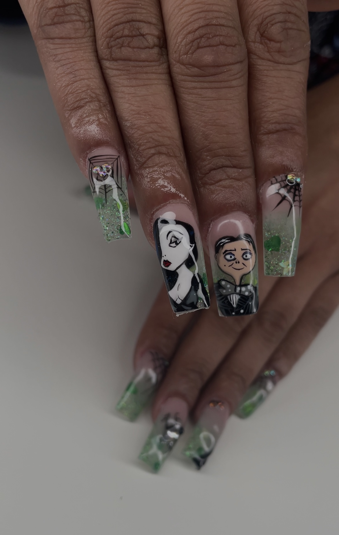 Lange vierkante acrylnagels met getekende figuren in zwart, wit en groen