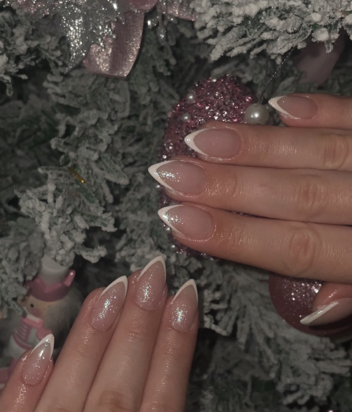 Amandelvormige French nagels met glitter tegen een besneeuwde kersttak